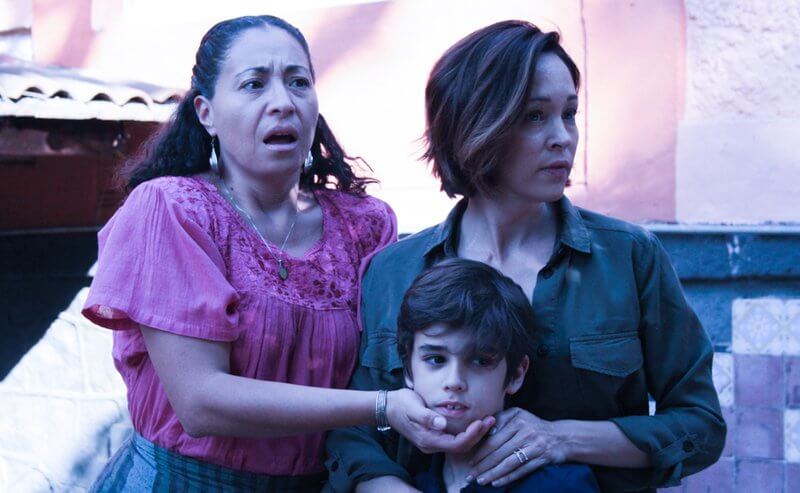 Two Hispanic women look shocked and are clutching at a small boy